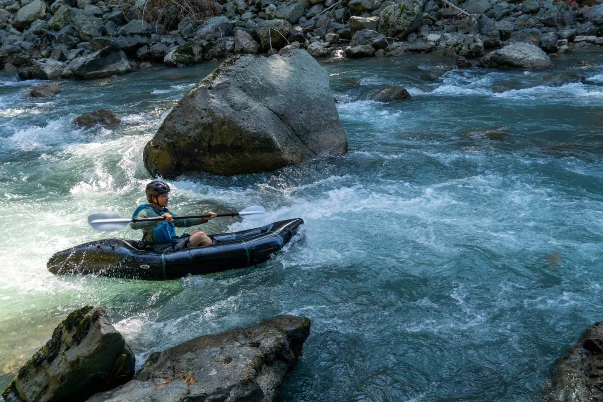 River kayaking with a person in an inflatable boat navigating swift waters among rocks outdoor adventure.