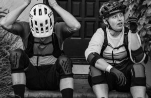 Helmeted mountain bikers resting after ride, outdoor adventure, cycling gear.